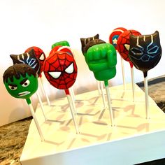 there are four cake pops with different faces on them in the shape of spider - man