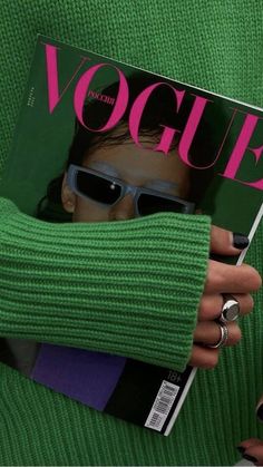 a woman in green sweater and sunglasses holding a magazine with the word'vogue'on it