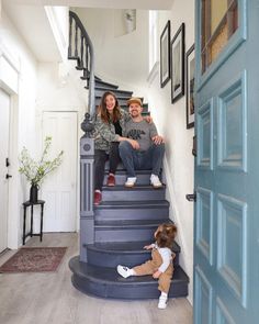 a man and woman sitting on top of a blue stair case next to a child