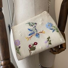 a white purse with flowers on it sitting on top of a mannequin's dummy