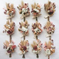 a bunch of flowers that are sitting on a white tablecloth with some dried flowers in the middle