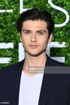 a man in a suit and white t - shirt poses for the camera at an event