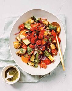 a white bowl filled with vegetables next to a small bowl of seasoning on top of a table