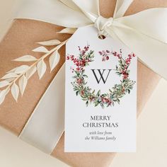 a christmas gift wrapped in brown paper with a white ribbon and monogramming on it