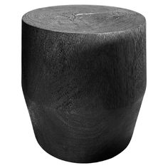 a black wooden stool sitting on top of a white floor next to a tree trunk