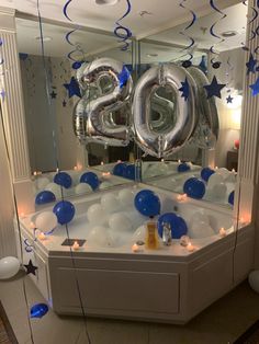 a bathtub with balloons and streamers in the shape of numbers on it, surrounded by candles