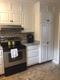 a kitchen with white cabinets and black appliances