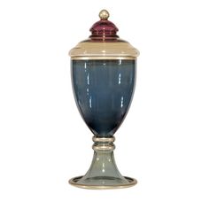 a blue and gold vase with a red lid on the top is sitting in front of a white background