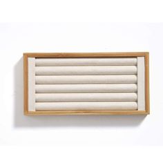 an empty wooden box with white linens on the inside and bottom, against a white wall