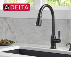 the delta faucet is next to a plate of food on the kitchen counter