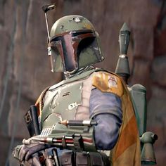 boba fett from star wars standing in front of a rock wall with his hand on his hip