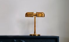 a gold desk lamp sitting on top of a black cabinet