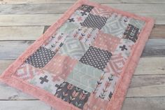 a pink and black patchwork quilt sitting on top of a wooden floor