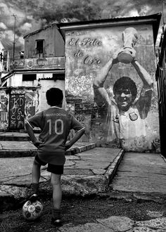 a young boy playing with a soccer ball in front of a graffiti covered wall and stairs