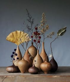 a group of vases sitting on top of a wooden table filled with flowers and plants