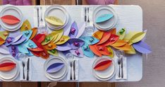 the table is set with paper flowers and place settings