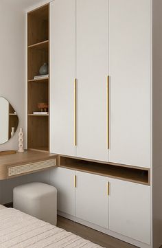 a bedroom with white cupboards and a mirror on the wall next to a bed