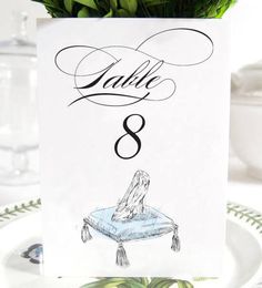 a table number card with a drawing of a woman sitting on top of a boat