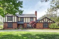 a large brick house sitting in the middle of a lush green field with lots of trees