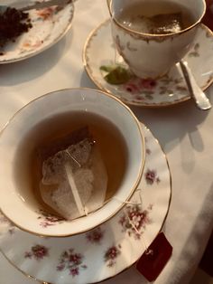 two teacups filled with liquid and ice on top of a white table cloth