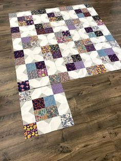 a patchwork quilt is laying on top of a wooden floor with the center piece missing