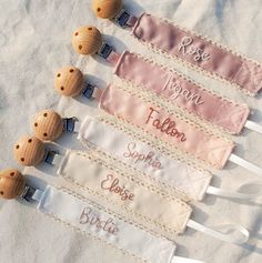 four wooden name tags with ribbons attached to them on a white cloth covered tablecloth