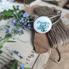 An original bracelet with a hand-painted cabochon from  porcelain!The flowers pattern was painted by hand on a porcelain cabochon, special paints and then fired at the right temperature. The drawing is very small, each element is painted under the microscope, miniature painting.The ring is in a romantic style. The bracelet is very elegant. Cabochon is made of Chinese porcelain and bound in a brass base in gold. diameter of a porcelain cabochon - 2,5 cm ( 1")diameter: 6.5 x 5.5 cm ( 2.6 x 2.2")No Forget Me Nots Flowers, Hand Painted Necklace, Painted Jewelry, Unique Handmade Jewelry, Romantic Gifts, Ceramic Jewelry, Romantic Style, Porcelain Painting, Custom Necklace