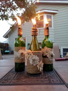 three wine bottles decorated with burlocks and flowers are sitting on a patio table