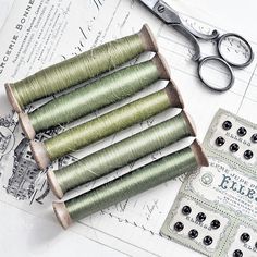 four spools of thread sitting next to some scissors