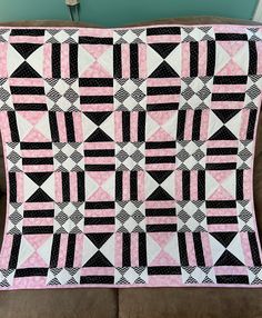 a pink and black quilt sitting on top of a couch