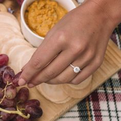 a close up of a person's hand with a ring on their finger near grapes