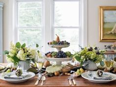 the table is set with plates and bowls of fruit, flowers, and wine glasses