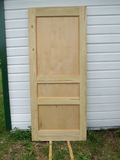 a wooden door sitting in the grass next to a building