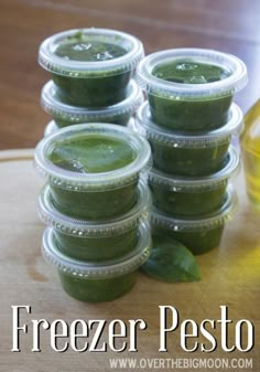 several jars of green pest sitting on top of a wooden table