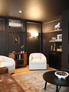 a living room with two white chairs and a black table in front of the couch