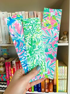 a person holding up some colorful papers in front of bookshelves