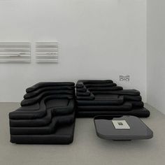 a large black couch sitting on top of a floor next to a footstool