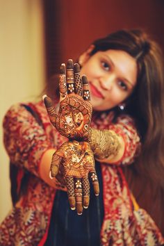 a woman holding up her hands with henna designs on it's palms and arms