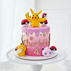 a pink cake with pokemon characters on it and the number four is decorated in gold