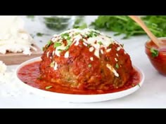 meatballs covered in marinara sauce and parmesan cheese on a white plate