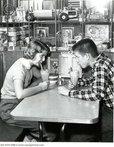 two people sitting at a table with cups