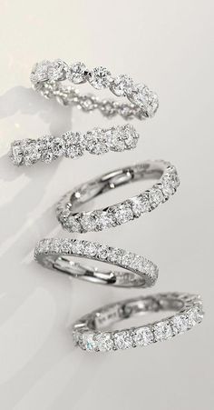 three white gold and diamond spiral rings on a white background, with the top one being surrounded by smaller round brilliant cut diamonds