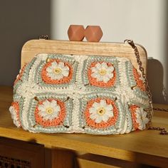 an orange and white crocheted purse sitting on top of a wooden table next to two eggs