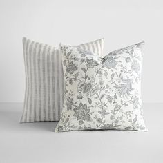 two pillows sitting next to each other on top of a white table with grey and white stripes