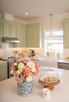 a vase filled with flowers sitting on top of a kitchen counter next to an oven