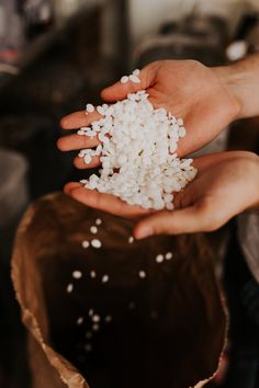 two hands holding white rice over a chocolate cake