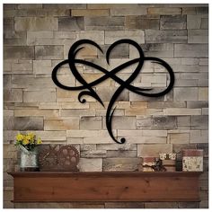 a fireplace with a heart shaped iron decoration on it's mantle next to a brick wall