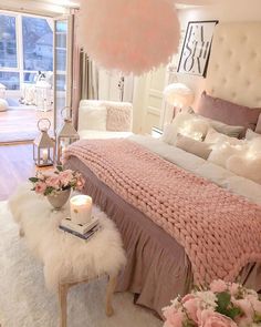 a bedroom decorated in pink and white with flowers on the bed, lights hanging from the ceiling