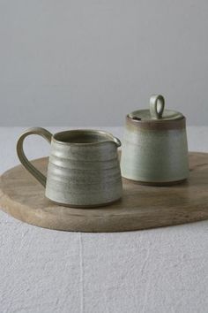 two ceramic mugs sitting on top of a wooden tray