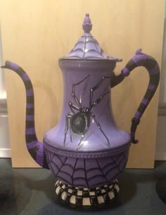 a purple ceramic tea pot with a spider on it